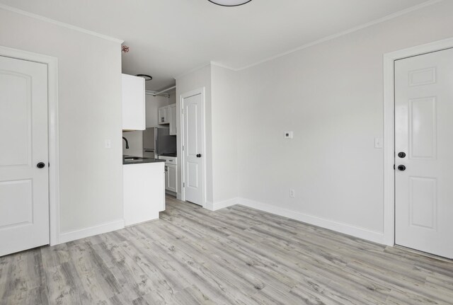 unfurnished living room with ornamental molding, light hardwood / wood-style flooring, and sink