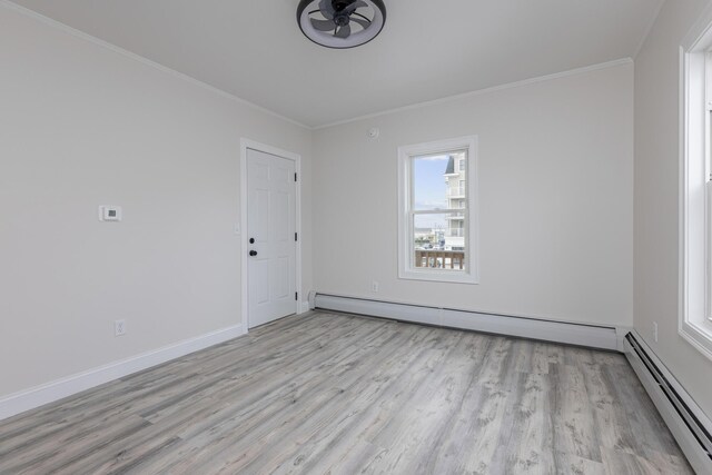 unfurnished room with a baseboard heating unit, crown molding, and light hardwood / wood-style floors