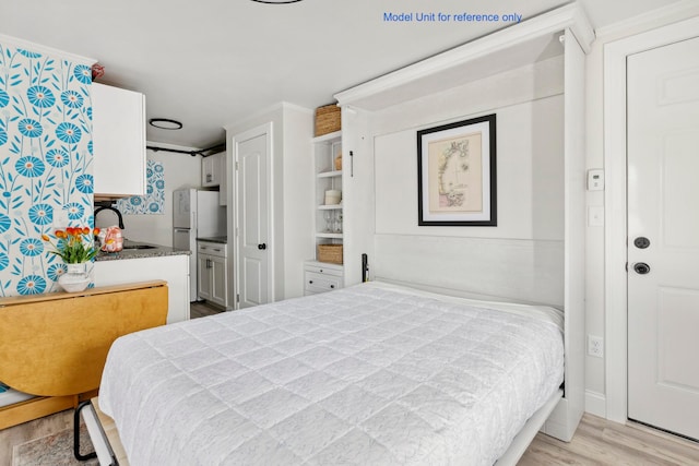 bedroom with light wood-type flooring, white refrigerator, and sink