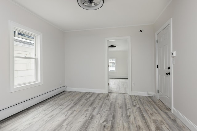 empty room with a baseboard heating unit, baseboards, wood finished floors, and crown molding