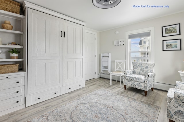 sitting room featuring a baseboard radiator, crown molding, and wood finished floors