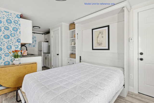 bedroom with light wood finished floors, a sink, and freestanding refrigerator