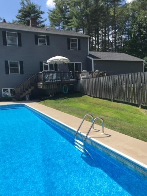 view of swimming pool with a wooden deck and a lawn