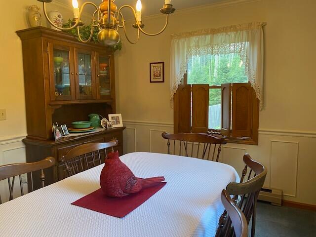 carpeted dining space with baseboard heating and a notable chandelier