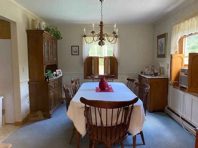 dining space featuring cooling unit, a baseboard radiator, a notable chandelier, light carpet, and ornamental molding