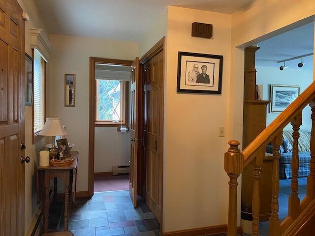 hallway featuring dark tile patterned flooring, rail lighting, and a baseboard radiator