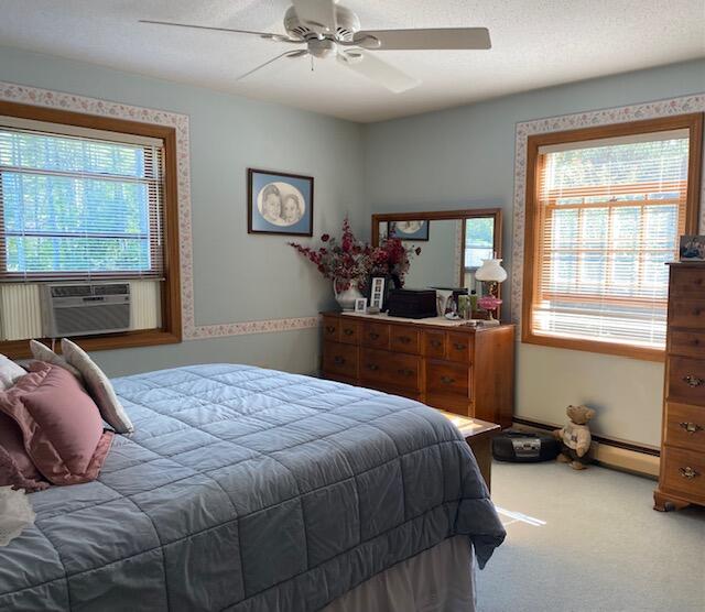 bedroom with cooling unit, ceiling fan, baseboard heating, and carpet