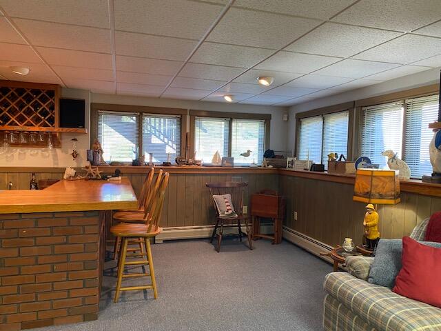 interior space featuring a baseboard heating unit, a paneled ceiling, and carpet flooring