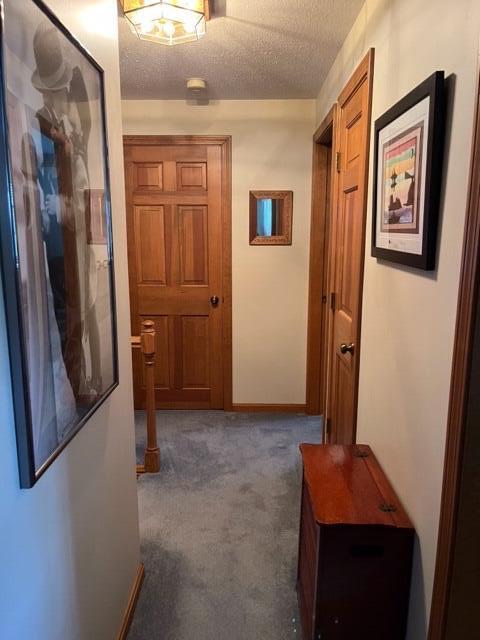 hall featuring dark carpet and a textured ceiling