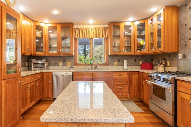 kitchen featuring light stone counters, light wood-style floors, a sink, and stainless steel appliances