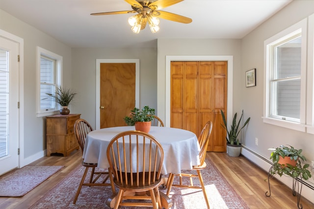 dining area featuring baseboards, light wood-type flooring, a baseboard heating unit, and a ceiling fan