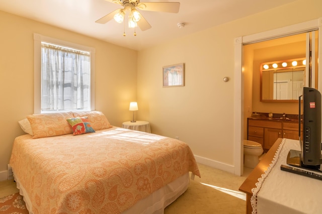 bedroom with a ceiling fan, light carpet, connected bathroom, and baseboards