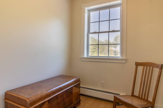 living area with light wood-style flooring and a baseboard heating unit