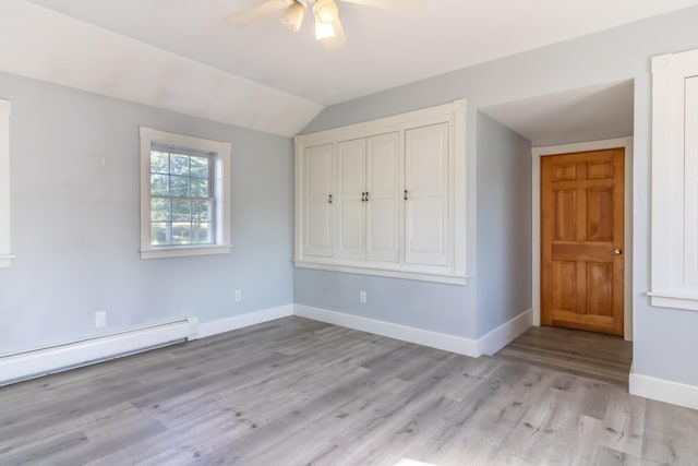 unfurnished bedroom with vaulted ceiling, baseboards, light wood-style floors, ceiling fan, and baseboard heating