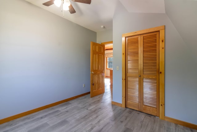 unfurnished bedroom featuring baseboards, vaulted ceiling, a closet, and wood finished floors