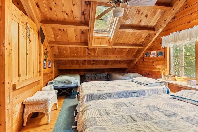 bedroom with multiple windows, wood-type flooring, and wooden walls