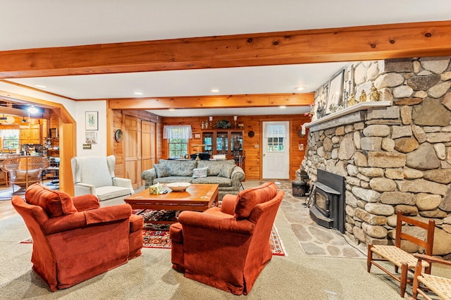 carpeted living room with a wood stove and a stone fireplace