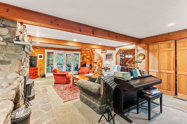 living room featuring beamed ceiling, a stone fireplace, and wooden walls