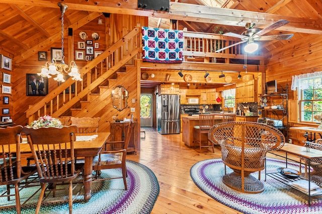 dining room featuring light wood-type flooring, beam ceiling, and wooden walls