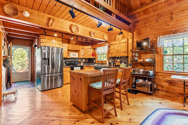 kitchen featuring black electric range, light hardwood / wood-style flooring, stainless steel fridge with ice dispenser, decorative backsplash, and wooden walls