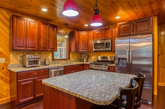 kitchen featuring a center island, dark hardwood / wood-style floors, a breakfast bar area, hanging light fixtures, and appliances with stainless steel finishes