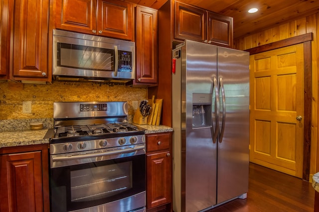 kitchen with light stone counters, appliances with stainless steel finishes, dark hardwood / wood-style flooring, and decorative backsplash