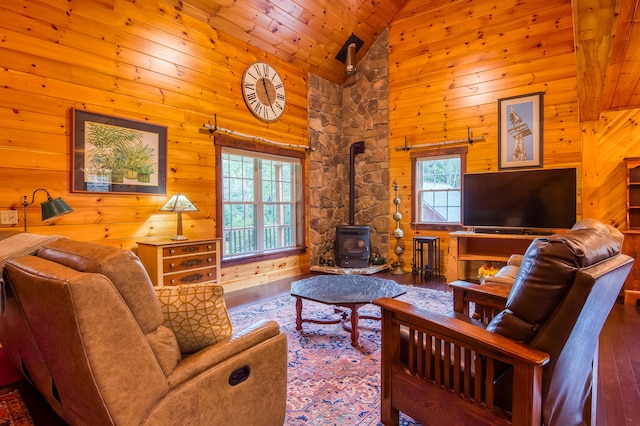 living room with high vaulted ceiling, hardwood / wood-style flooring, a wood stove, and a wealth of natural light