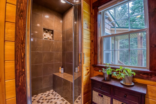 bathroom featuring vanity, wooden walls, and tiled shower