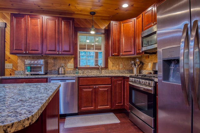 kitchen with pendant lighting, wood walls, dark wood-type flooring, stainless steel appliances, and wooden ceiling