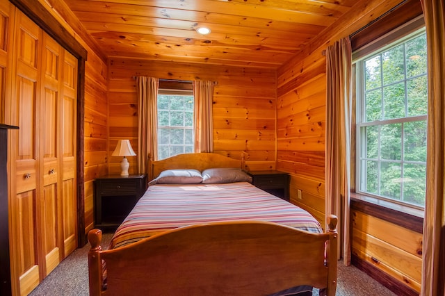 carpeted bedroom with wood ceiling, wooden walls, and a closet