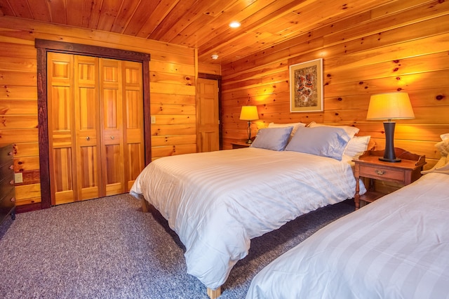 bedroom with wooden ceiling, carpet flooring, wood walls, and a closet