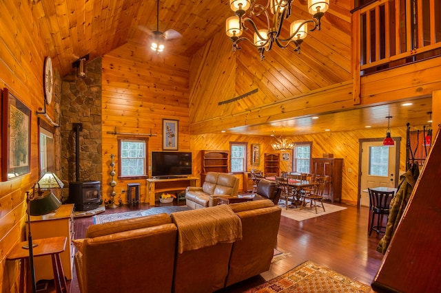 living room with hardwood / wood-style flooring, a notable chandelier, a wood stove, wood walls, and high vaulted ceiling