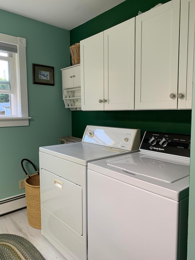 clothes washing area featuring washing machine and clothes dryer, light hardwood / wood-style floors, a baseboard radiator, and cabinets