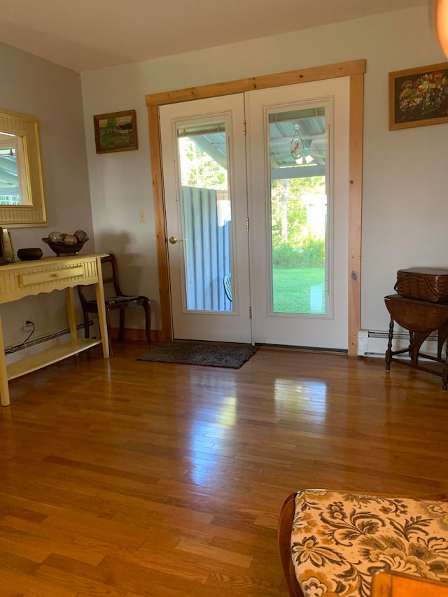 doorway to outside with hardwood / wood-style floors and a baseboard heating unit