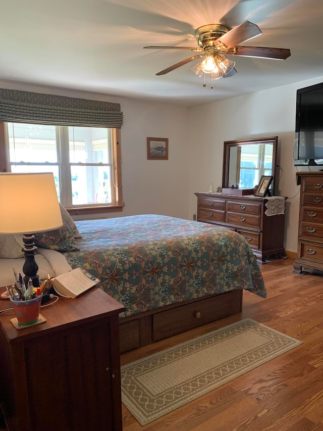 bedroom featuring ceiling fan, hardwood / wood-style flooring, and multiple windows