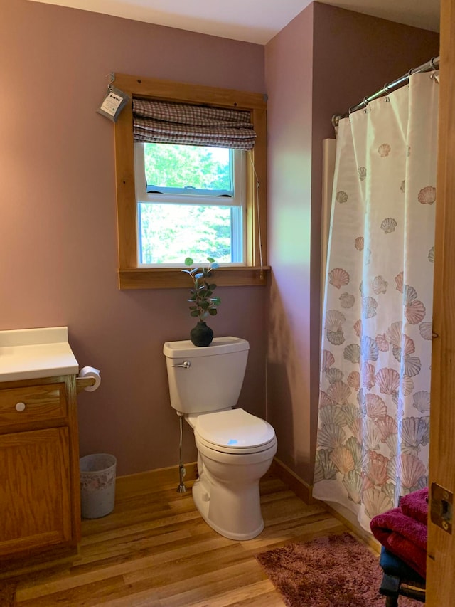 bathroom featuring wood-type flooring, walk in shower, vanity, and toilet