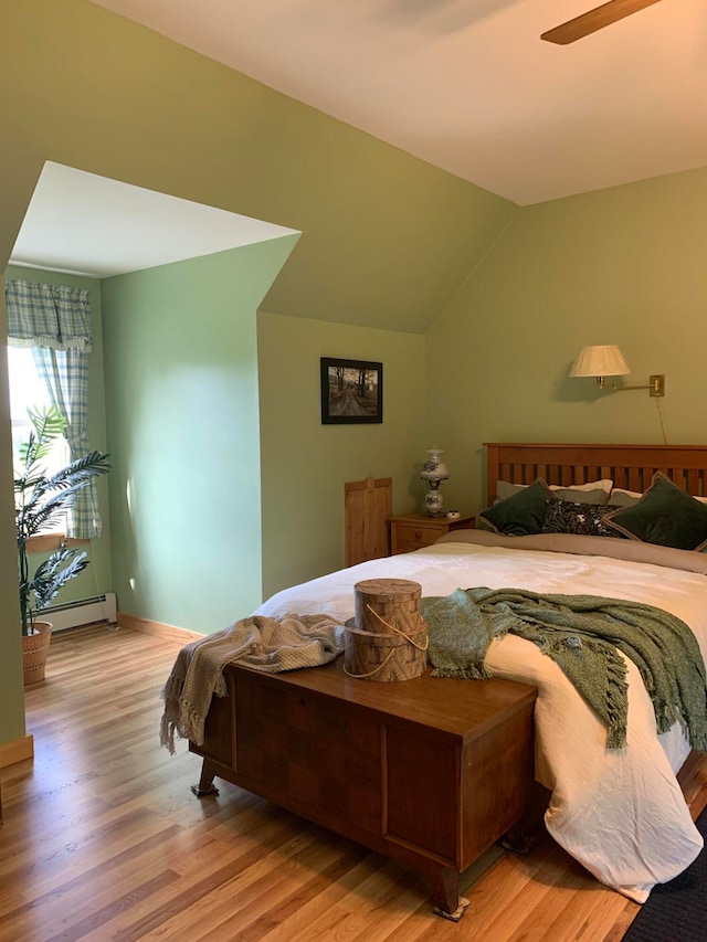 bedroom with a baseboard radiator, lofted ceiling, ceiling fan, and hardwood / wood-style flooring