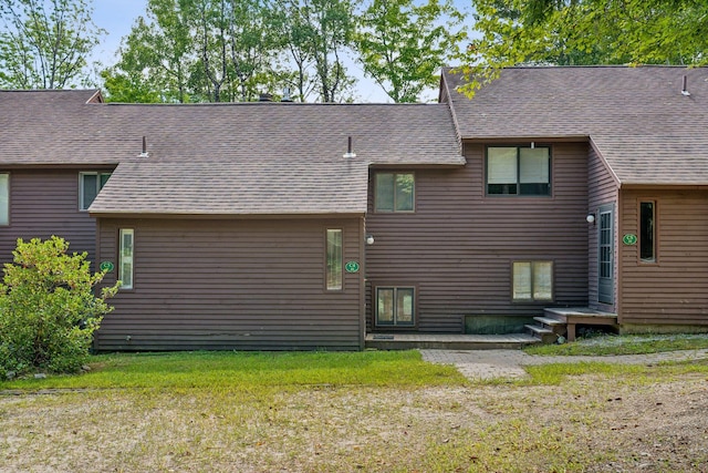 back of house featuring a patio, a lawn, and roof with shingles