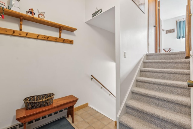 staircase with a baseboard radiator, tile patterned flooring, and baseboards