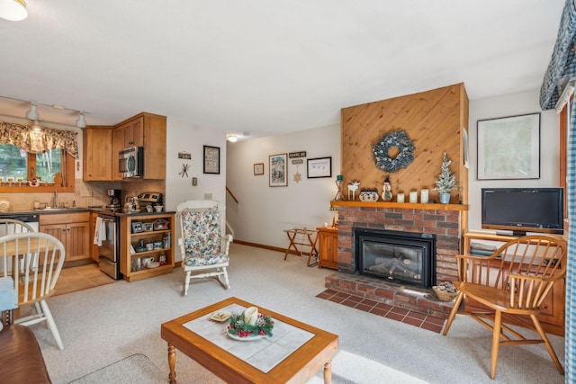 living room featuring a brick fireplace, baseboards, track lighting, and light colored carpet