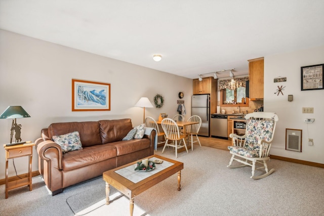 living area featuring baseboards, track lighting, visible vents, and light colored carpet