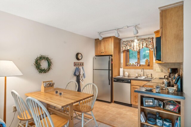 kitchen with track lighting, backsplash, stainless steel appliances, and sink