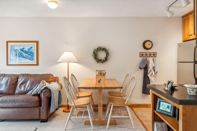 dining space featuring rail lighting and baseboards