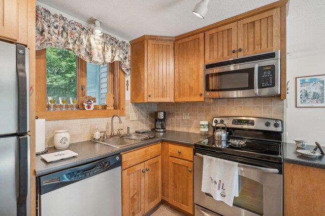 kitchen with a textured ceiling, sink, appliances with stainless steel finishes, and decorative backsplash