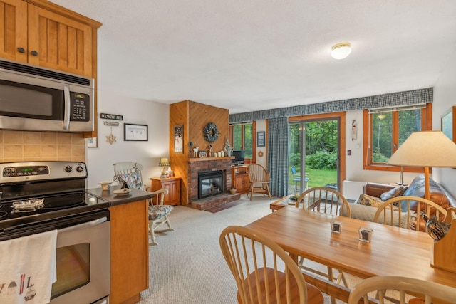 dining space featuring light carpet and a brick fireplace