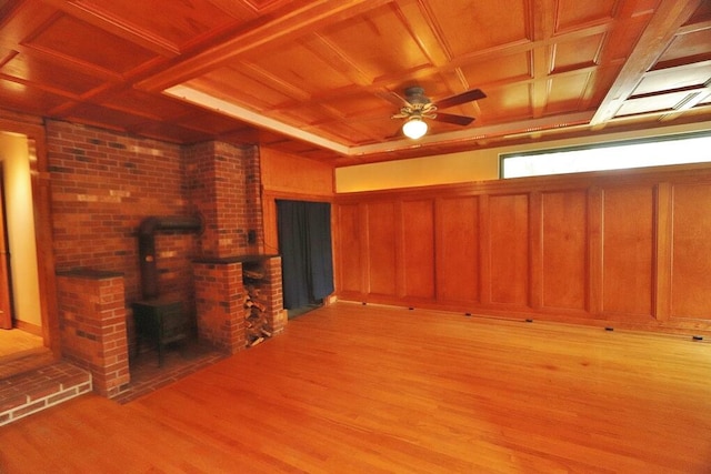 unfurnished living room featuring ceiling fan, a wood stove, wood ceiling, and light wood-type flooring