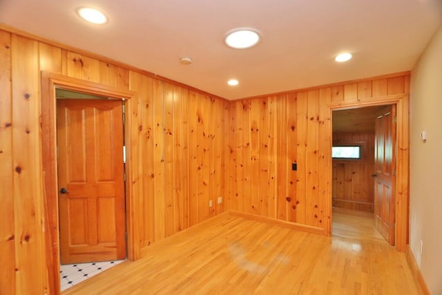 spare room with hardwood / wood-style flooring and wooden walls