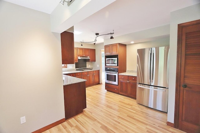 kitchen with rail lighting, light stone counters, stainless steel appliances, and light wood-type flooring