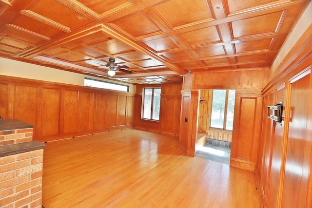 unfurnished living room with coffered ceiling, light hardwood / wood-style flooring, wood ceiling, and wood walls