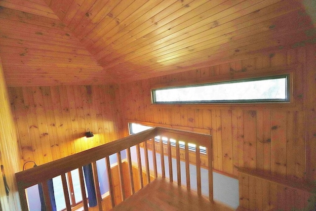 hallway featuring lofted ceiling, wooden walls, and wooden ceiling